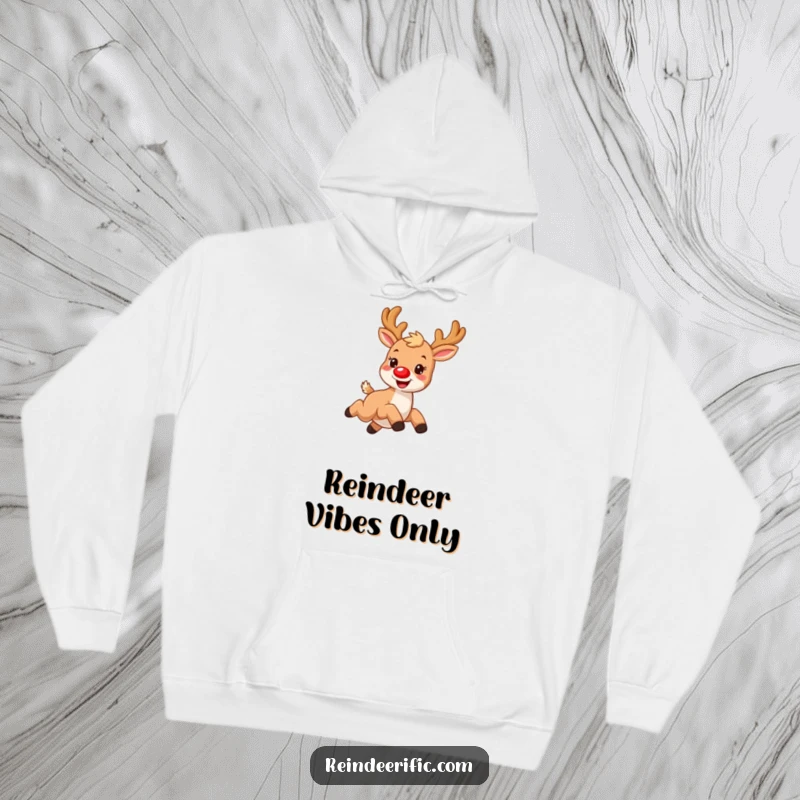 Funny hoodie showcasing a small, furry reindeer with a glowing red nose, joyfully leaping over a flurry of snowflakes.