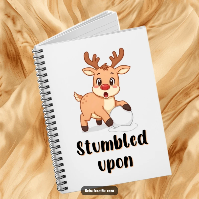 Funny reindeer with a surprised expression caught mid-stumble over a snowball on a notebook.